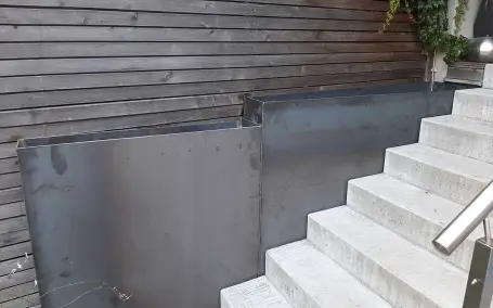 Maßgefertigte Hochbeete aus Rohstahl entlang einer Außentreppe