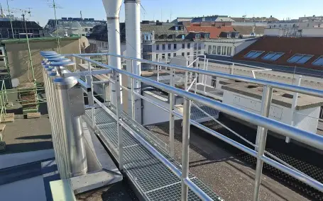 Verzinkter Wartungssteg mit Geländeranlage zwischen Kaminanlagen am Dach