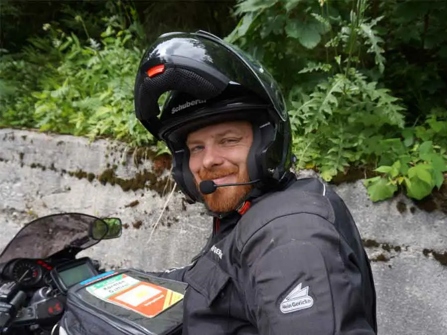 Hubert Knopfhart auf dem Motorrad mit Helm und Headset im Grünen