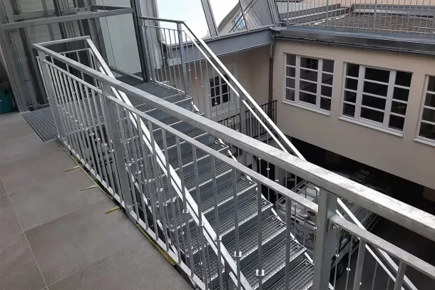 Metallgeländer und Treppe aus Stahl bei Gebäude mit Innenhof