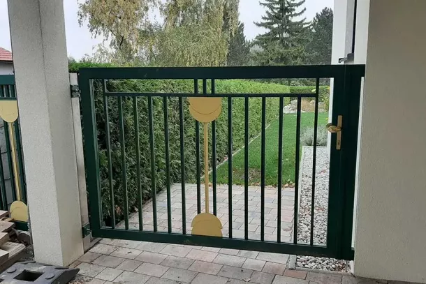Tor aus Metall mit Zierdetails, Einfahrt zu Garten mit Pflasterweg